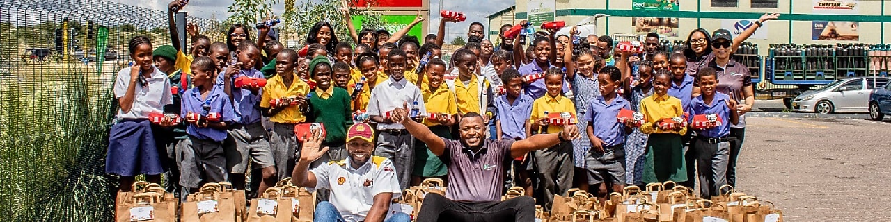 A group photo of 50 primary school learners from Aris and Golden Hills schools posing with the Vivo Energy Namibia team during the Fueling Young Minds event at a Shell service station.