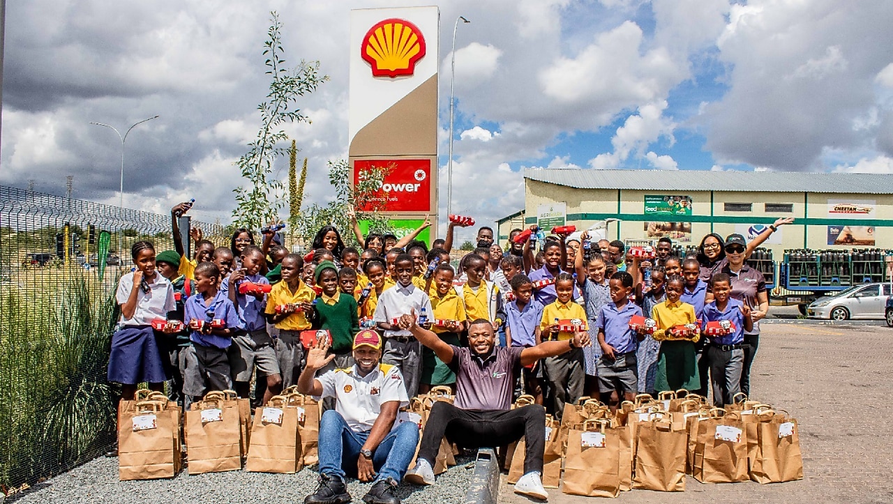 A group photo of 50 primary school learners from Aris and Golden Hills schools posing with the Vivo Energy Namibia team during the Fueling Young Minds event at a Shell service station.