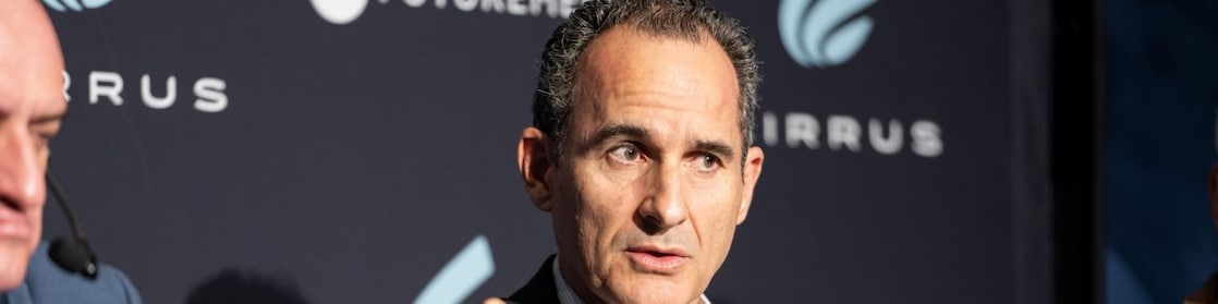 Shell delegate speaking into a microphone during a panel discussion with two others.