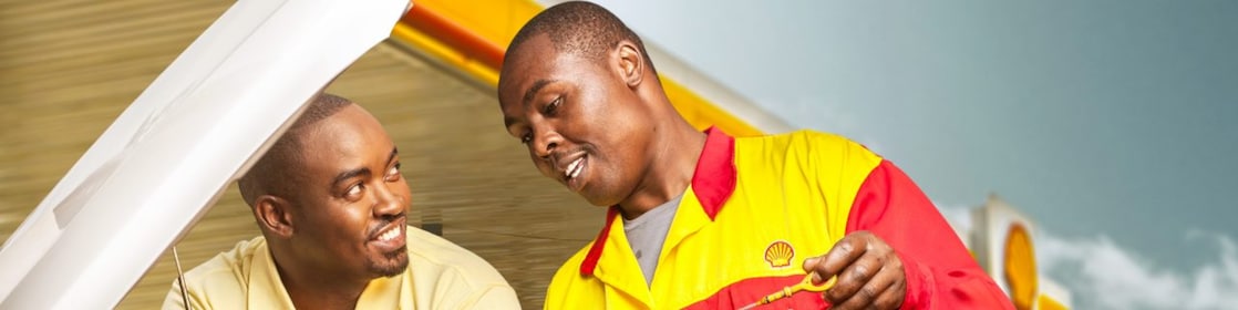 Service attendant standing over an car engine with an oil dip stick