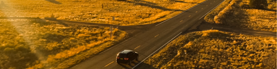Car driving alone on a remote sunny highway fueled by Shell Fuelsave Diesel.